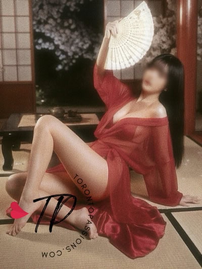 Woman in red kimono holding fan in traditional Japanese room.