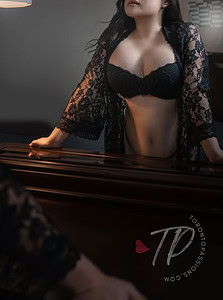 Elegant woman in black lace lingerie and robe in a dimly lit room.