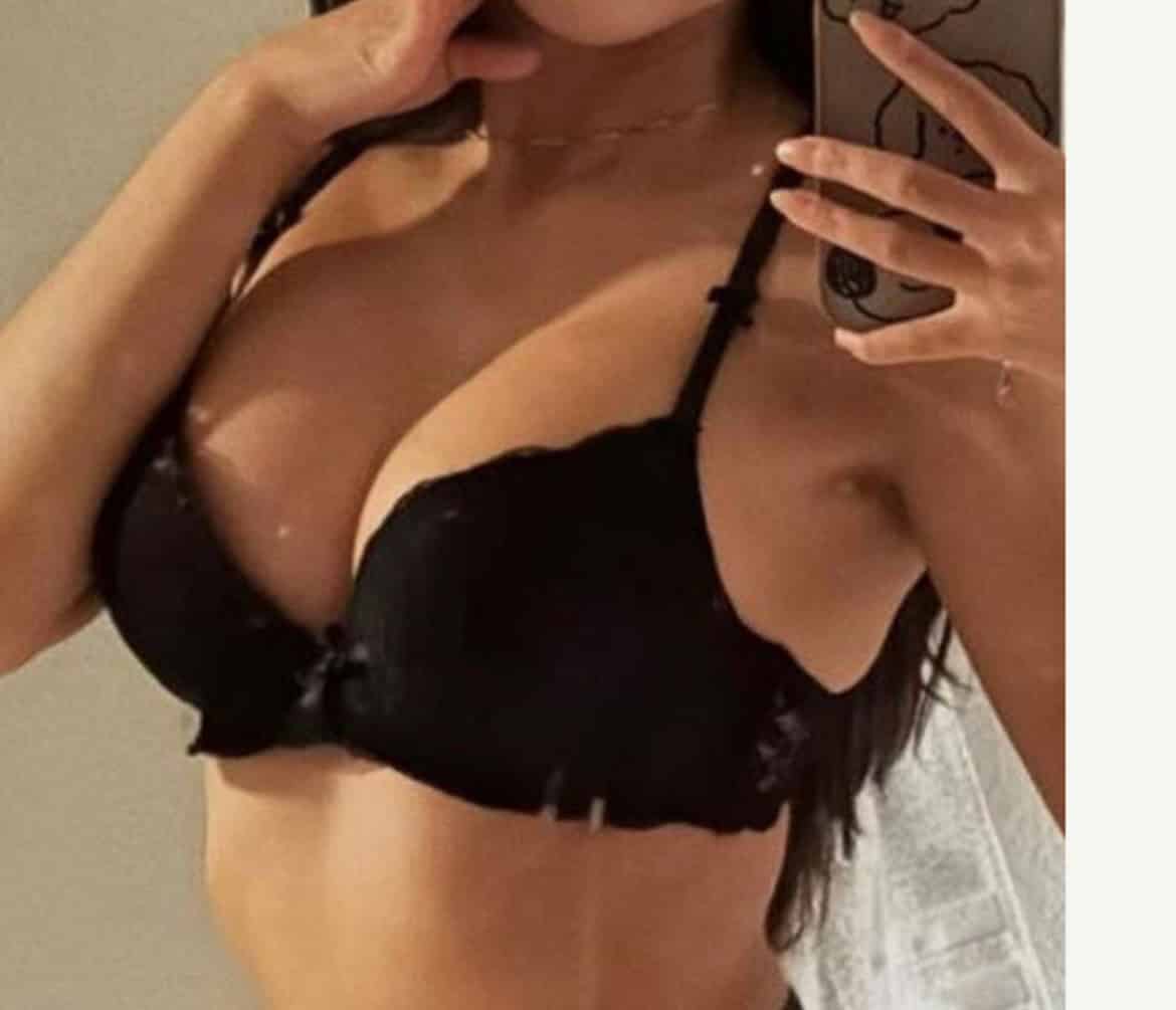 Close-up of a woman in black lingerie taking a mirror selfie.