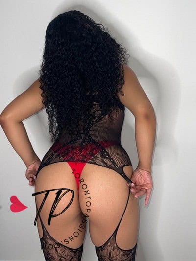 Curvy woman in black lace lingerie with red accents, back view.